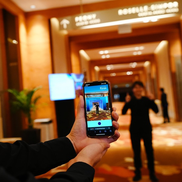 Dell-Technologies-Forum-Singapore-2023-PMG-4.jpg A pair of hands holding a smartphone that shows a man posing in front of a Dell Technologies Forum archway generated by AR technology.