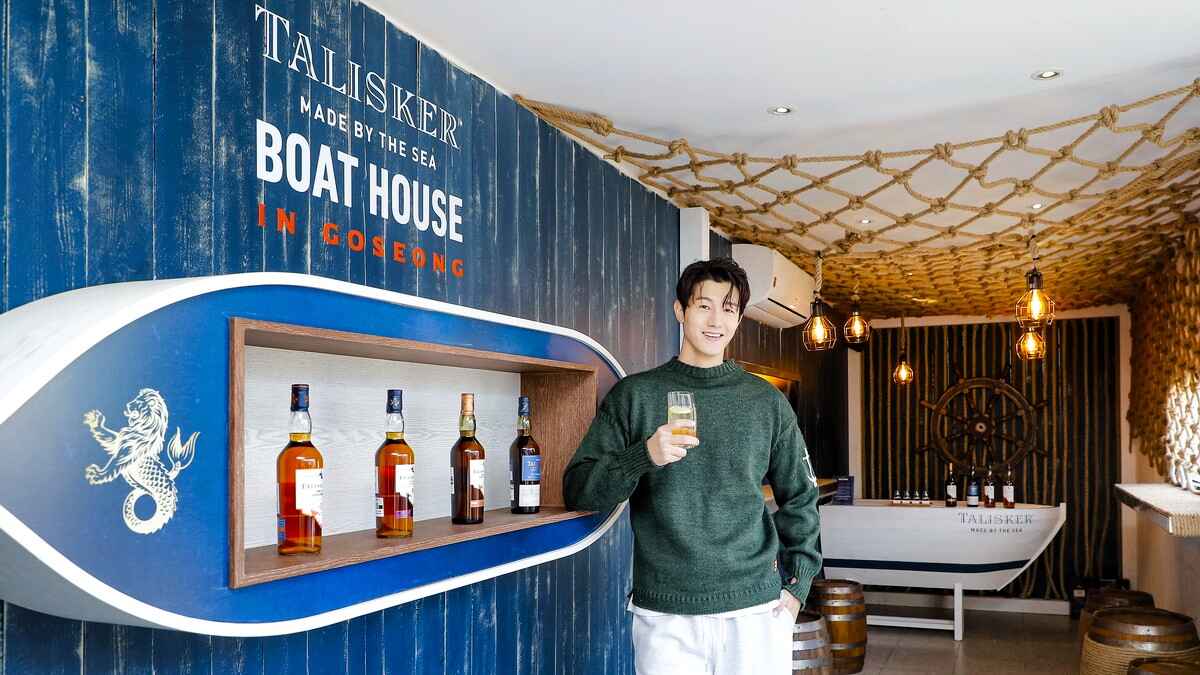Diageo-Talisker-Boathouse-pop-up-store-PMG-5.jpg Actor Li Ki-Woo stands in front of a bar counter that says Talisker Made by the Sea: Boathouse in Goseong, featuring Talisker whiskies.