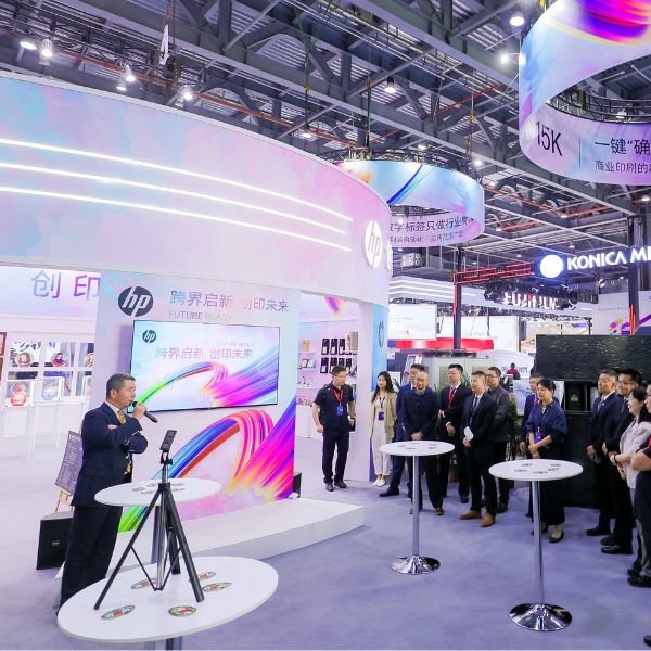 HP-Indigo-Print-China-2023-PMG-3.jpg Print China 2023 event attendees gathering at tables outside the HP Indigo Print 15K Digital Press booth, viewing a speaker presentation.